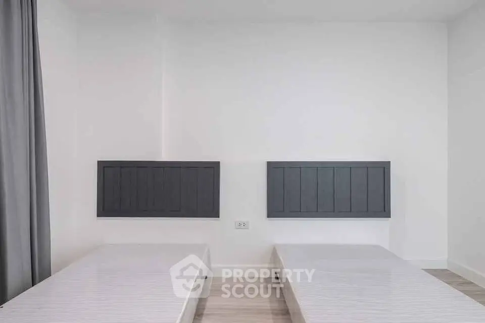 Minimalist bedroom with twin beds and modern headboards in a bright, airy space.