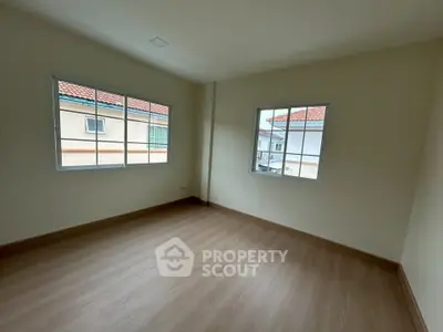 Spacious empty room with wooden flooring and large windows