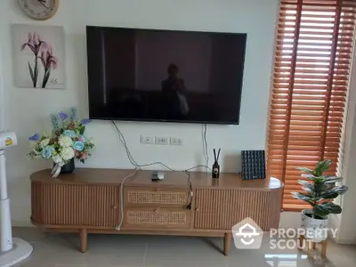 Modern living room with stylish TV stand and wall-mounted flat screen, accented by elegant decor and natural light.