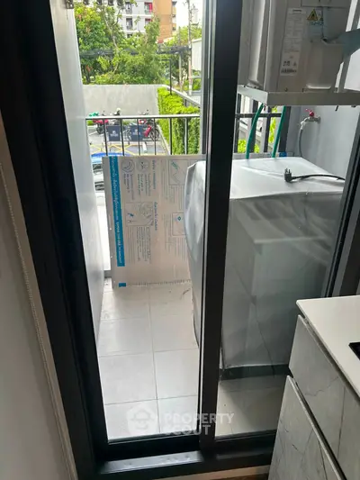 Compact balcony with washing machine and city view, ideal for urban living convenience.