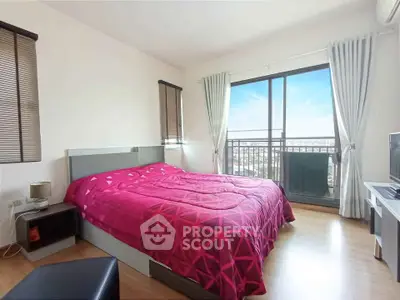 Bright bedroom with balcony and city view, featuring modern decor and natural light.