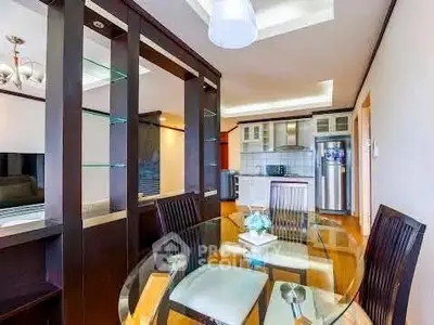 Modern dining area with glass table and stylish kitchen in open layout apartment.