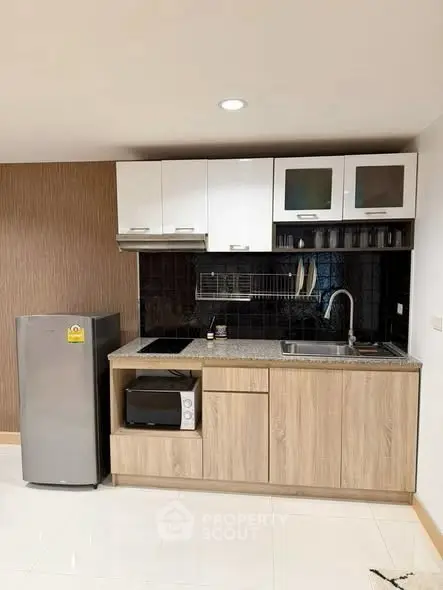 Modern kitchen with sleek cabinetry, compact fridge, and built-in appliances in a stylish apartment.