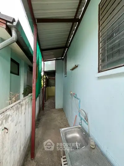 Outdoor utility area with sink and covered walkway in residential property
