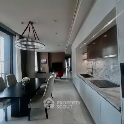 Luxurious open-plan kitchen and dining area with elegant chandelier and marble finishes.