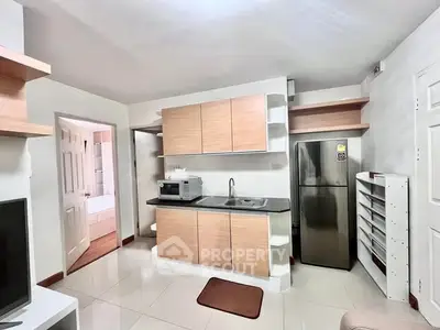 Modern kitchen with sleek cabinets and stainless steel appliances in cozy apartment.