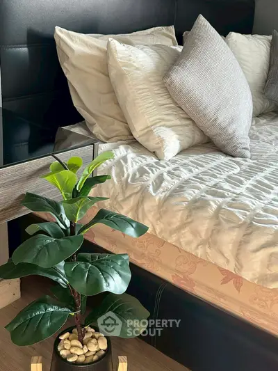 Cozy bedroom with stylish bedding and decorative plant for a serene ambiance.