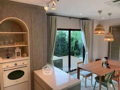 Modern kitchen with open layout and dining area overlooking a lush garden