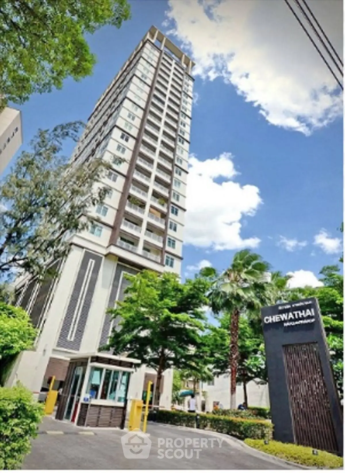 Modern high-rise building with lush greenery and clear blue sky.