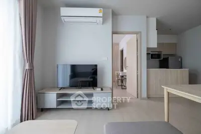 Modern living room with air conditioning and sleek kitchen in open layout apartment.