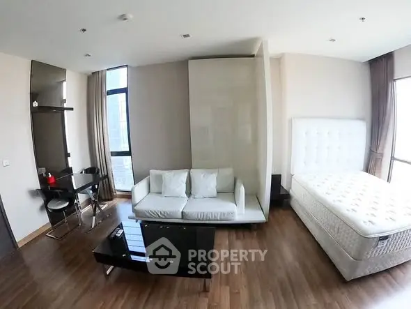 Modern studio apartment with stylish furniture and large windows for natural light.