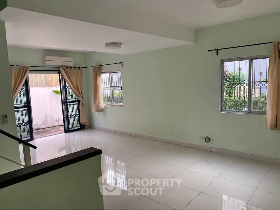 Spacious living room with large windows and garden view, perfect for family gatherings.