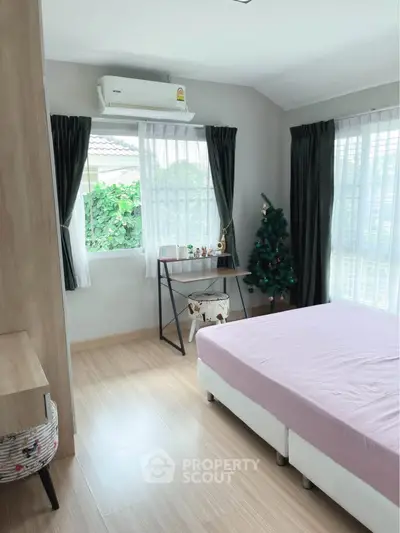 Bright and cozy bedroom with large windows and a festive touch, perfect for relaxation and comfort.