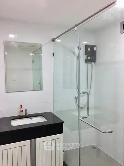 Modern bathroom with glass shower enclosure and sleek vanity in a contemporary home.