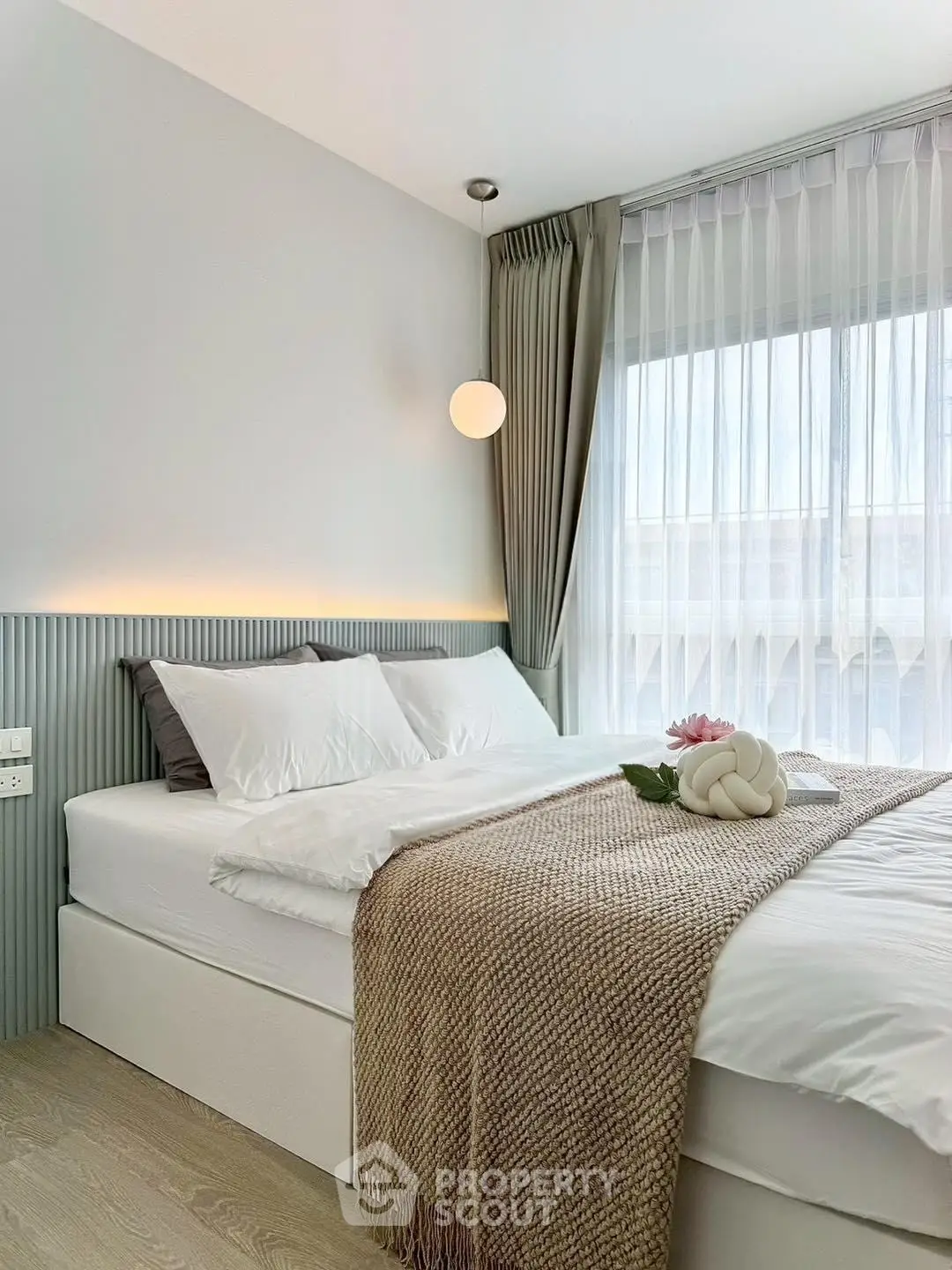 Modern bedroom with elegant decor and natural light, featuring a cozy bed and stylish lighting.