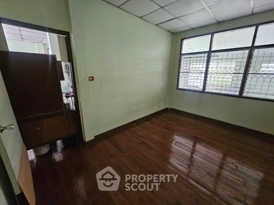 Spacious empty room with wooden flooring and large windows for natural light.