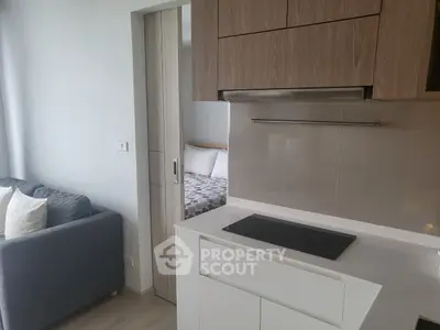 Modern compact kitchen with sleek cabinetry and cozy living area in contemporary apartment.