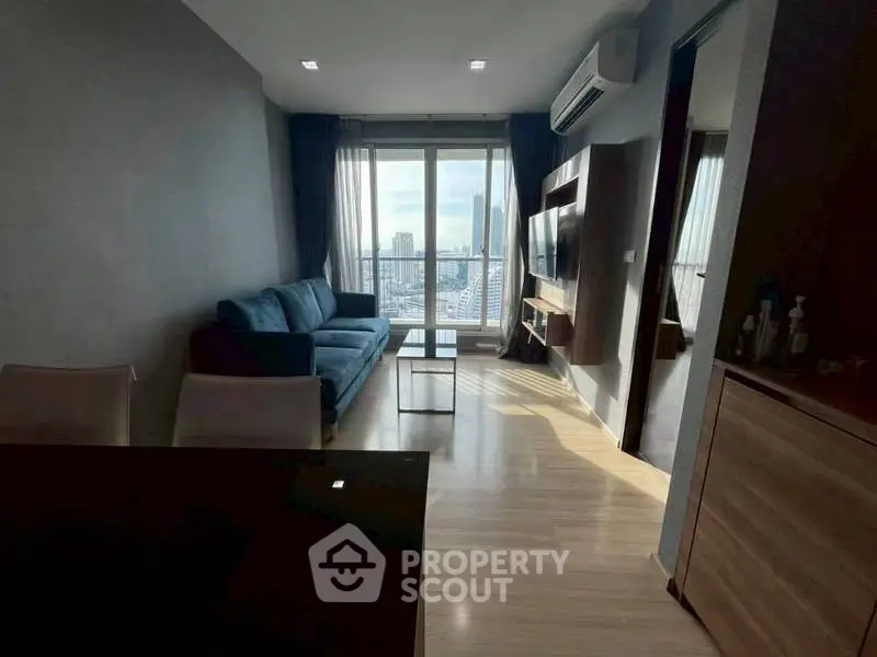 Modern living room with city view, featuring sleek furniture and large windows for natural light.