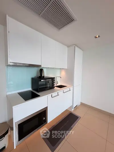Modern kitchen with sleek white cabinetry and built-in appliances in a contemporary apartment.