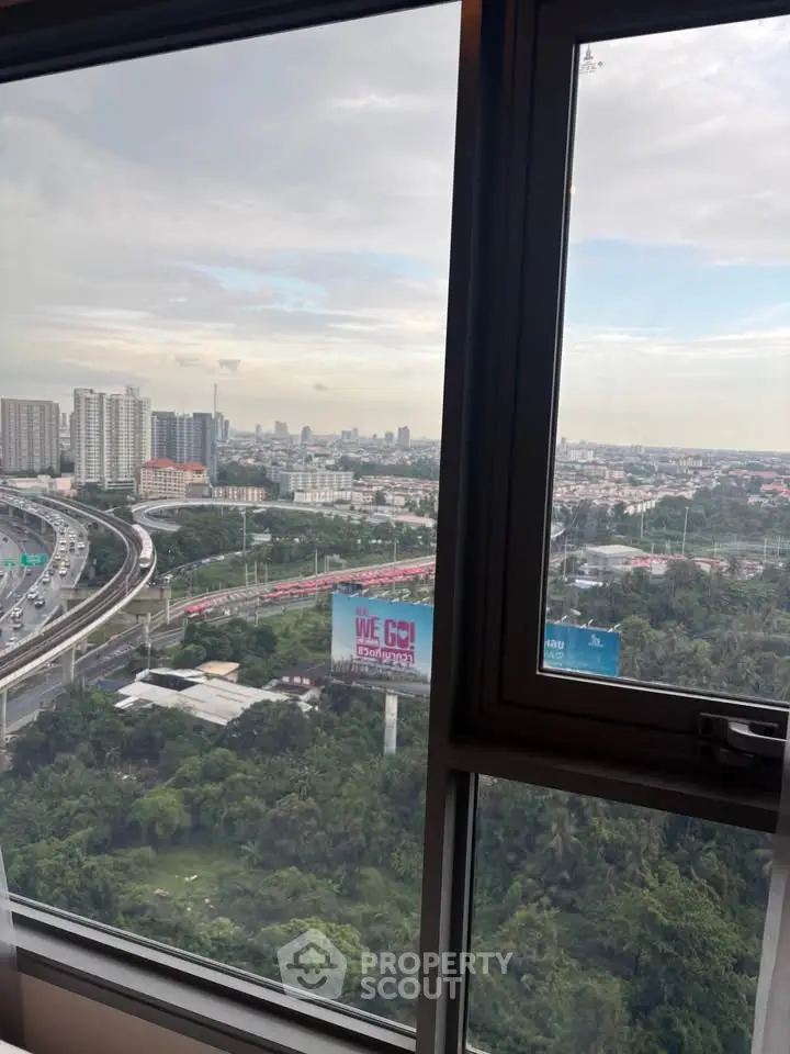 Stunning cityscape view from high-rise window showcasing urban skyline and lush greenery.