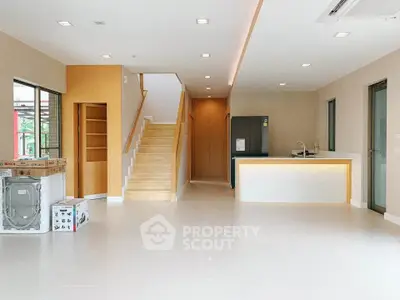 Spacious modern living area with open kitchen and staircase, featuring sleek design and ample natural light.