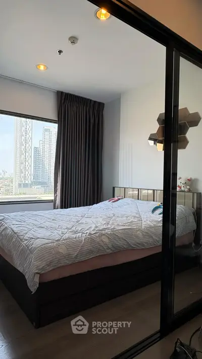 Modern bedroom with large window and city view, featuring stylish decor and cozy bedding.