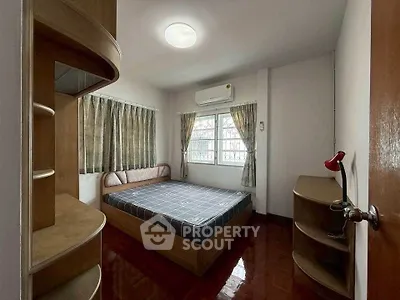 Cozy bedroom with wooden furniture and natural light, perfect for relaxation.