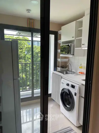 Modern kitchen with washing machine and balcony view in a stylish apartment.