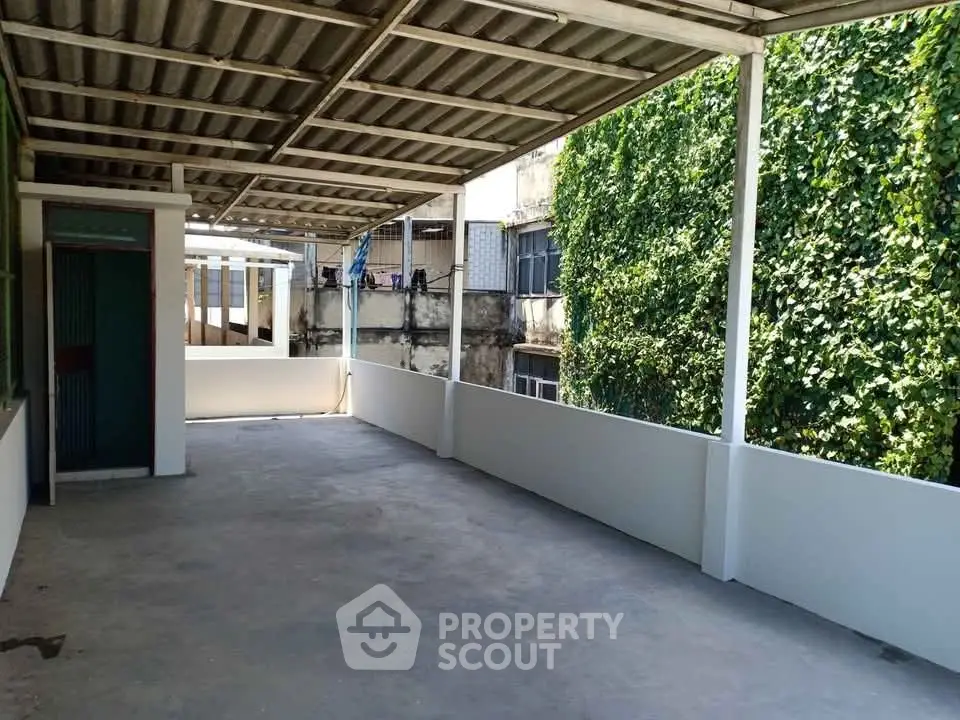 Spacious covered balcony with urban view and lush greenery