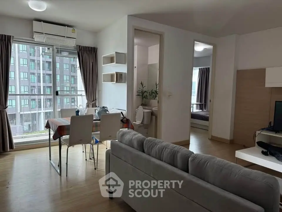 Modern apartment interior with open living and dining area, featuring large windows and stylish decor.