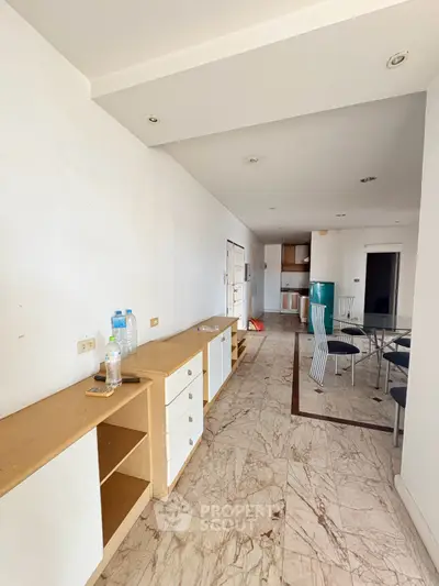 Spacious open-layout living area with modern kitchen and dining space, featuring marble flooring and ample natural light.