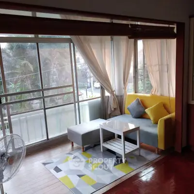 Bright living room with modern decor and large windows overlooking greenery.