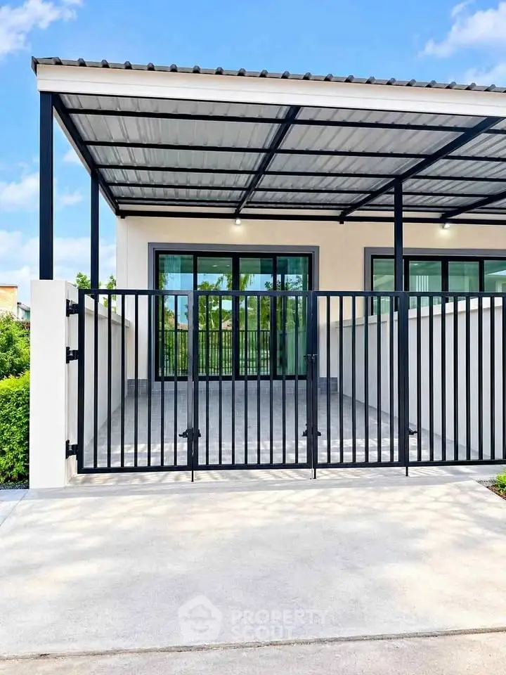 Modern house exterior with sleek metal gate and covered carport, showcasing contemporary design and functionality.