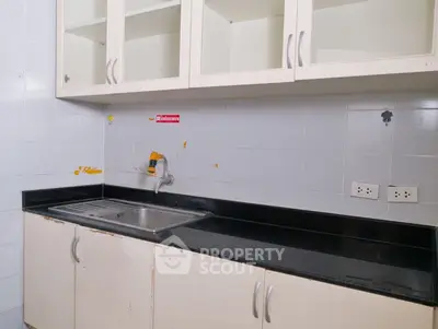 Spacious kitchen with sleek black countertop and ample cabinet storage.