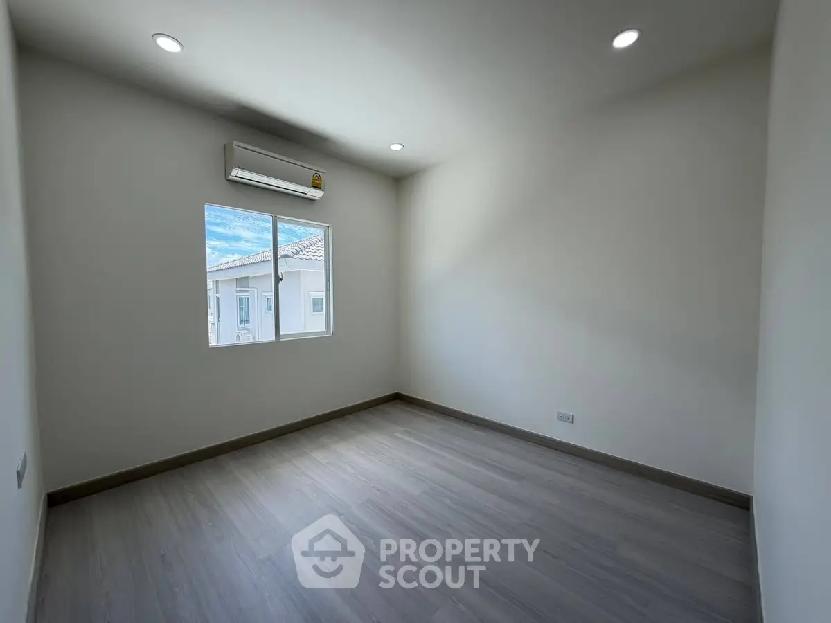 Spacious empty room with large window and air conditioning, perfect for customization.
