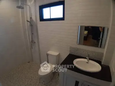 Modern bathroom with shower, toilet, and sink in a sleek tiled design.