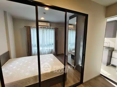 Modern bedroom with mirrored closet doors and adjacent kitchen view