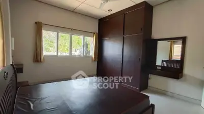 Spacious bedroom with large window and built-in wardrobe, offering natural light and ample storage.