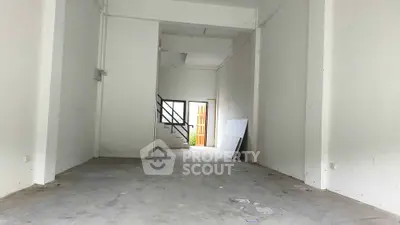 Spacious empty room with high ceiling and staircase, ideal for customization.