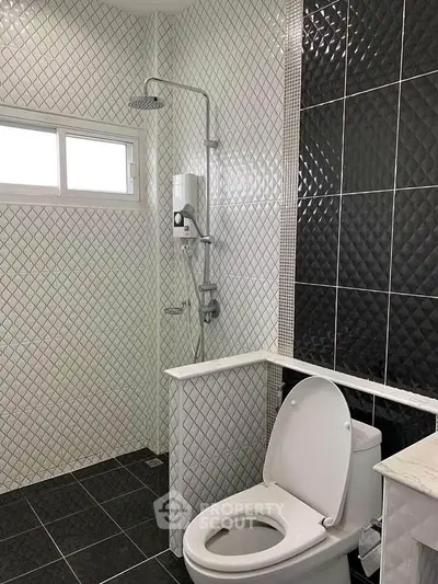 Modern bathroom with stylish black and white tiles and sleek fixtures.
