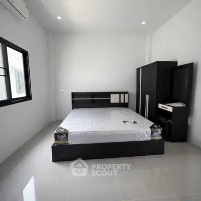 Modern minimalist bedroom with sleek black furniture and large window for natural light.