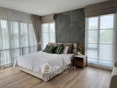 Elegant bedroom with modern decor and large windows offering natural light.