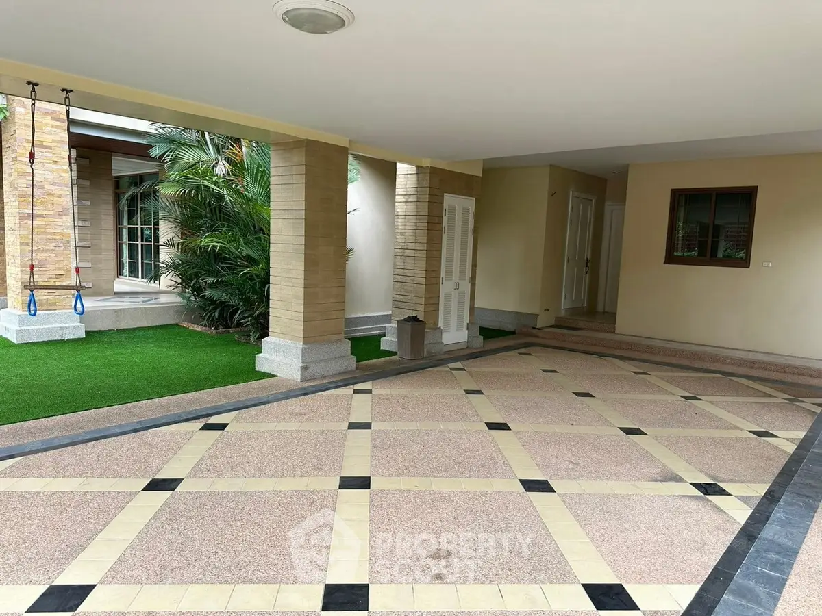 Spacious covered parking area with elegant tile design and lush greenery.