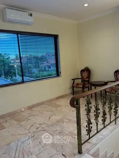 Elegant living area with marble flooring and large window offering scenic views, featuring classic chairs and air conditioning.