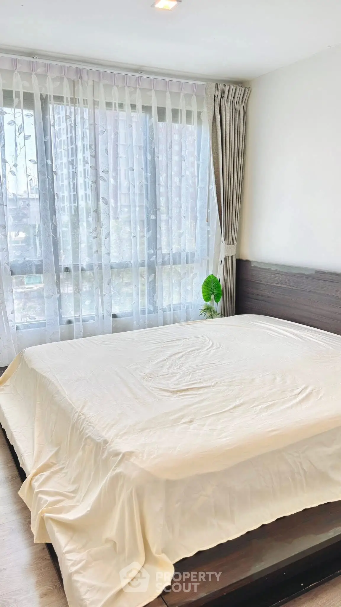 Spacious bedroom with large windows and elegant curtains in modern apartment.