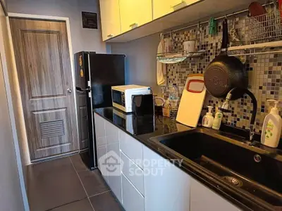 Modern kitchen with sleek cabinetry and mosaic backsplash, featuring a black sink and stainless steel appliances.