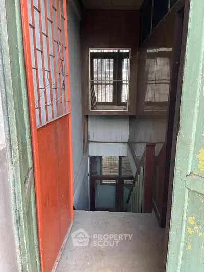 Narrow staircase leading to a lower level with metal and wooden elements, ideal for renovation.