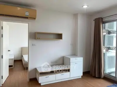 Modern apartment interior with wooden flooring, air conditioning, and natural light from large windows.