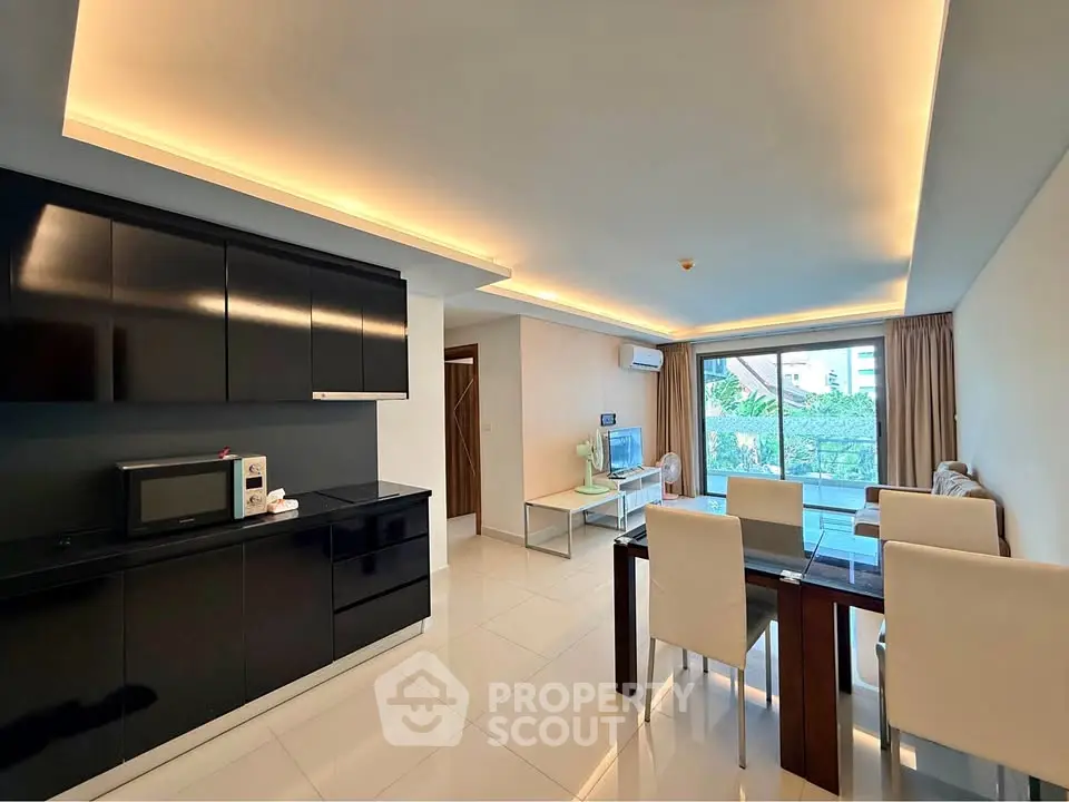 Modern open-plan living room with sleek kitchen and dining area, featuring elegant lighting and large windows.