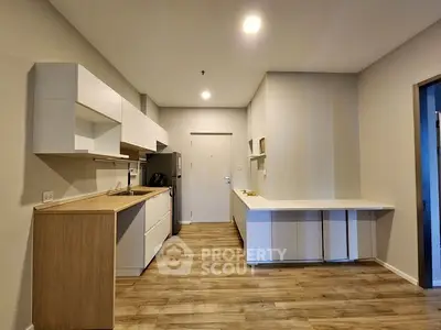 Modern kitchen with sleek cabinetry and wooden flooring in a contemporary apartment.
